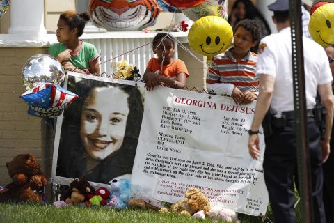 Children hold a sign and balloons in the yard of Gina DeJesus' family home in Cleveland on May 7.