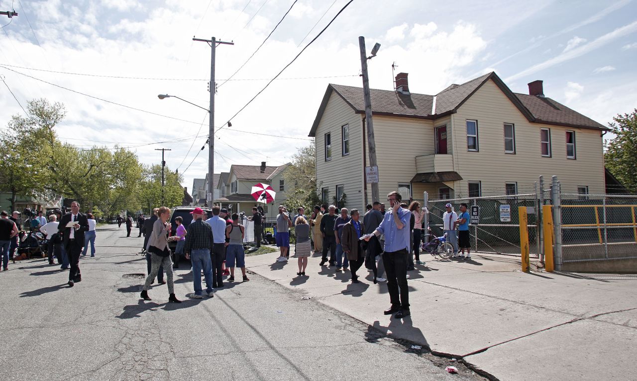 Bystanders and media gather on May 7 along Seymour Avenue in Cleveland near the house where the three women were held captive.