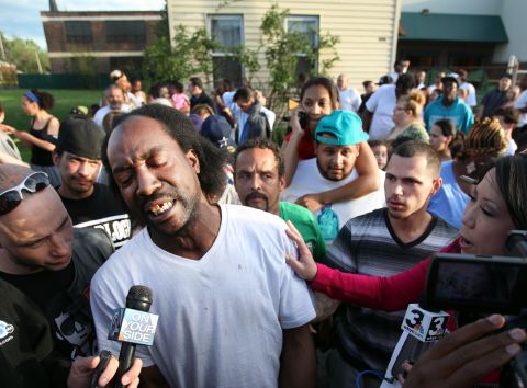 Neighbor Charles Ramsey talks to media as people congratulate him on helping the kidnapped women escape on May 6, 2013. He helped knock down the door after he heard screaming inside.
