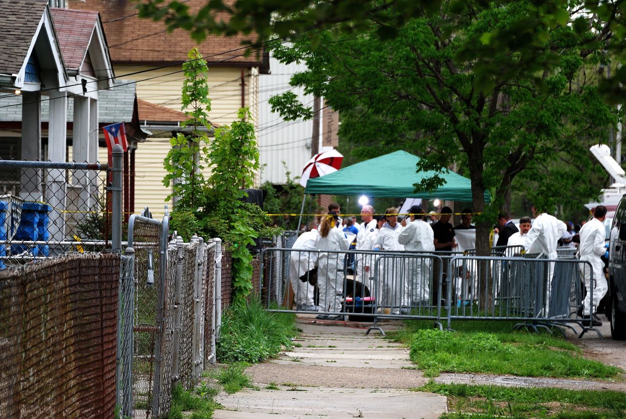 An FBI forensics team meets outside the house where three women were held as they investigate the property.