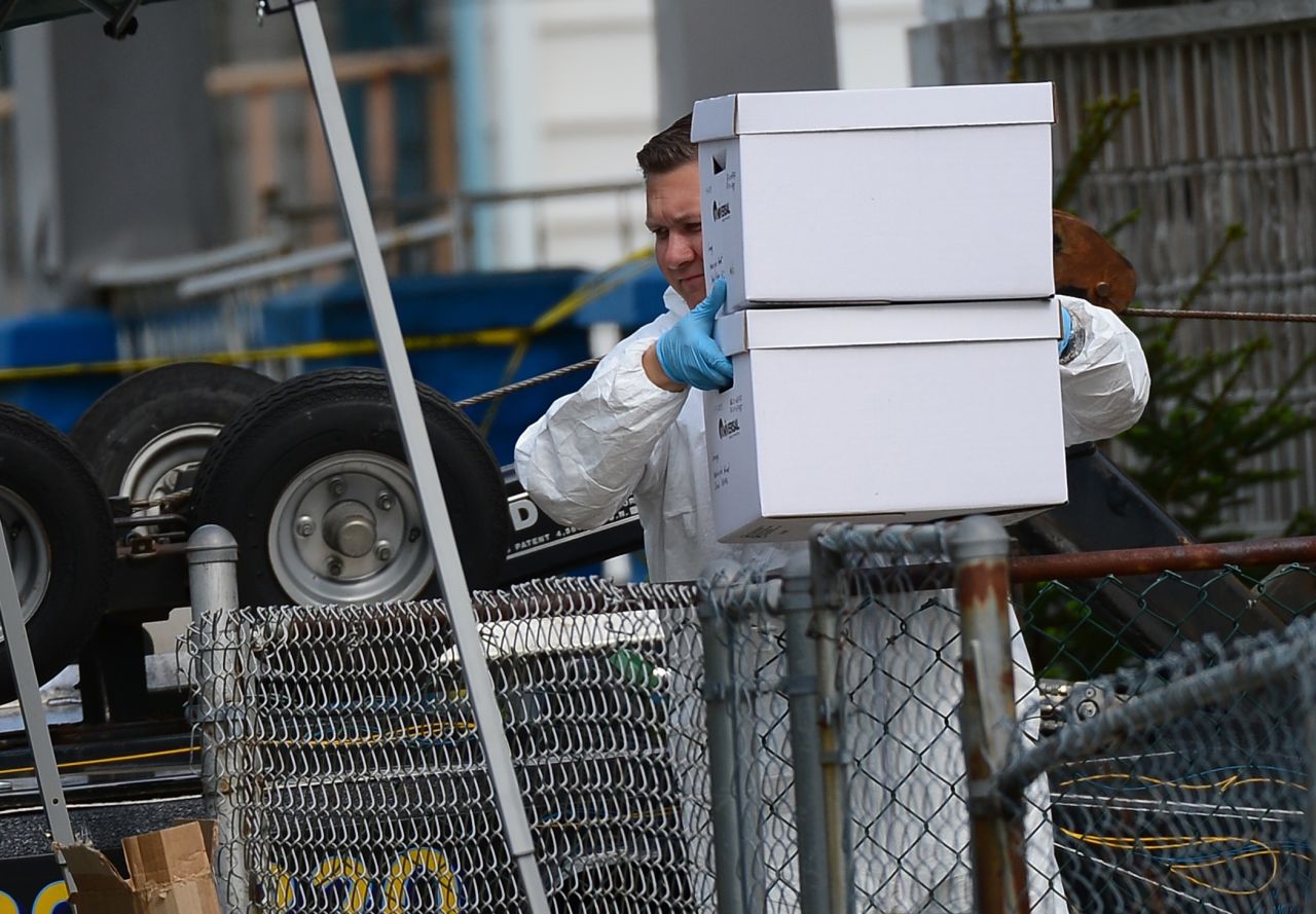 An FBI forensics team member removes evidence from the house.