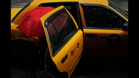 A woman exits a cab during a rainstorm on Wednesday, May 8, in New York.