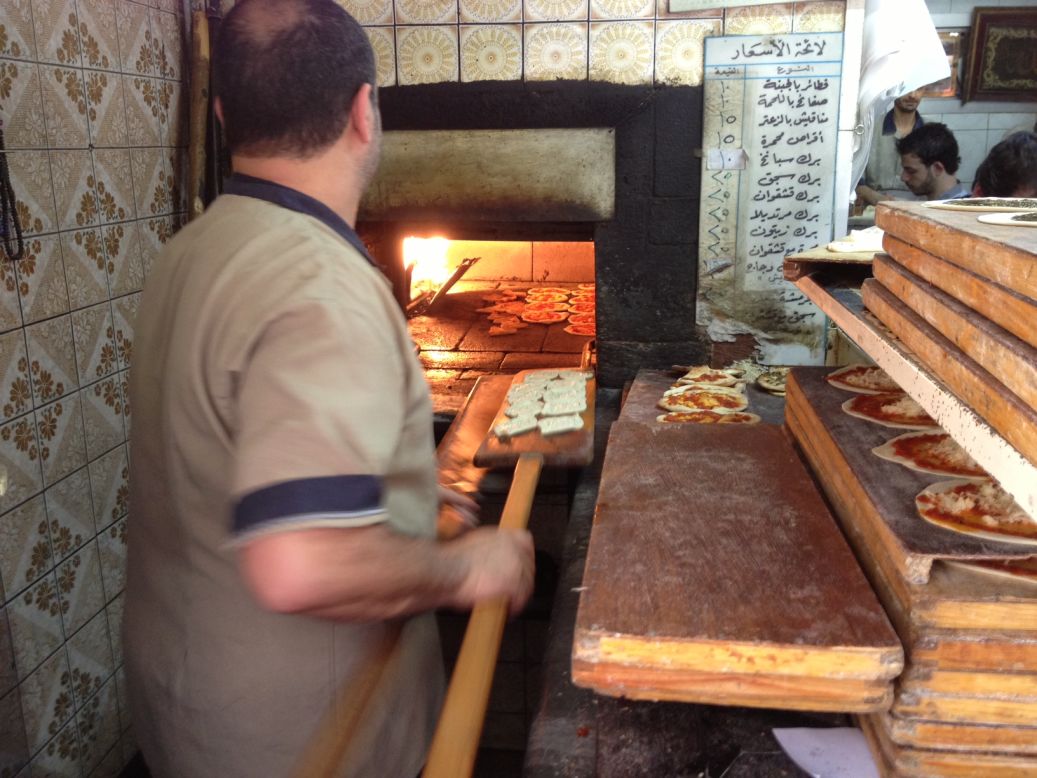 A baker makes zatar, a pastry akin to a mini-pizza with spices on top. Small bakeries offering cheap, tasty food are abundant in Damascus, and are usually full. However since the war began prices in the souk have soared and many goods are in short supply.
