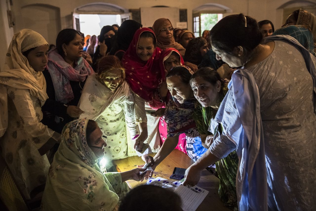 Pakistani women jostle to receive their ballot papers prior to casting their ballot at a polling station on May 11, in the Old City of Lahore, Pakistan.
