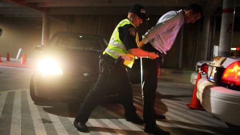 A police officer arrests a driver who failed a field sobriety test at a DUI traffic checkpoint in Miami, Florida. 