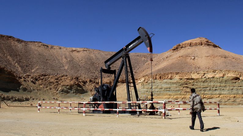 A security worker walks by an oil drill on March 23 at the al-Ghani oil field, owned by the Harouge Oil Operations company, near the city of Waddan.
