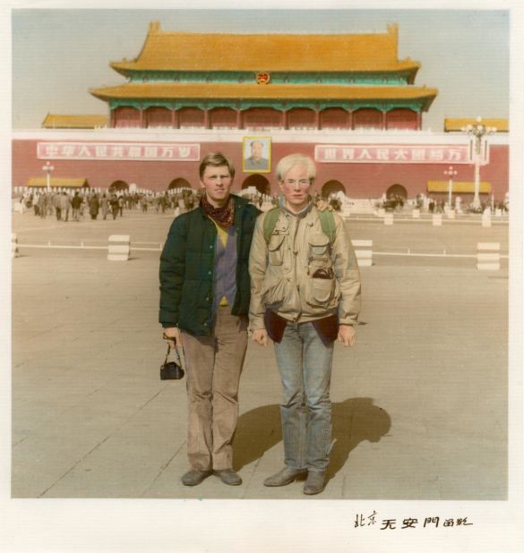 Christopher Makos (L) and Andy Warhol (R) had their picture taken in front of Tiananmen Square by one of the photographers hanging around the area.  Back in the U.S., they received the hand-colored photo in the mail a few months later.