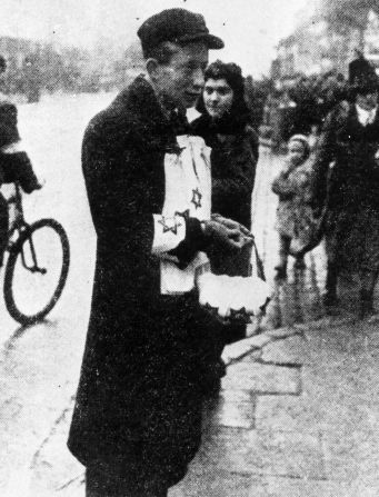 A street vendor in Warsaw ghetto sells yellow armbands featuring the star of David, which had to be worn visibly by all Jews in Warsaw at all times. 