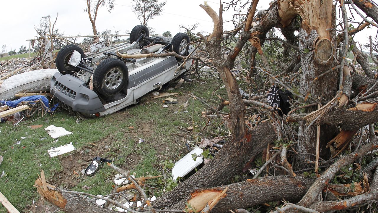 An upturned vehicle lies next to an uprooted tree on Thursday, May 16, in Granbury, Texas.