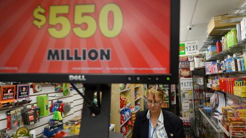 A woman buys a ticket near a sign for the Powerball lottery in New York on May 16. The odds of winning the jackpot are 1 in 175 million.