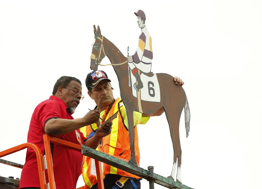 Workers paint the weather vane at the Pimlico Race course to match the colors worn by Oxbow and his jockey. 