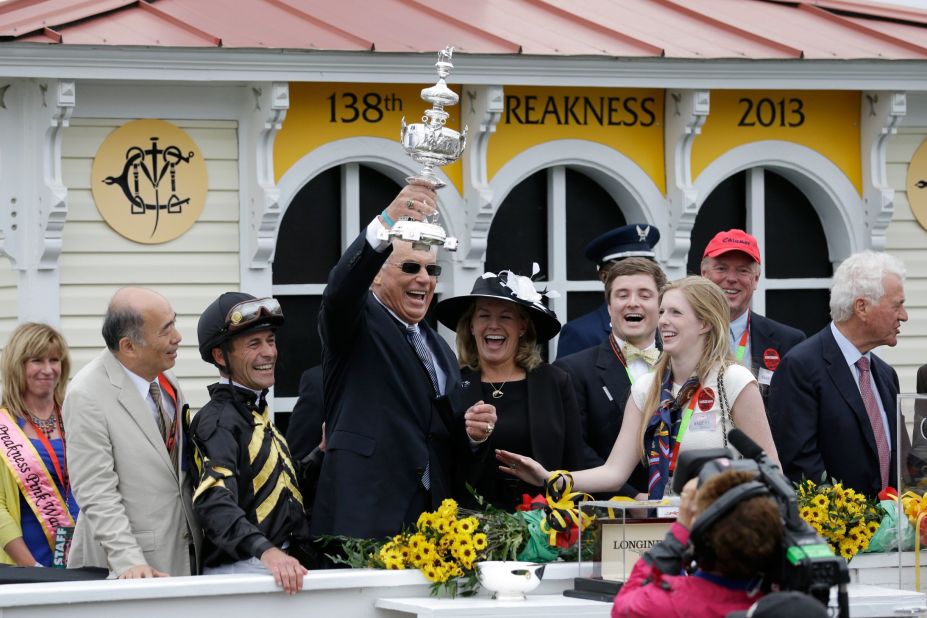 Trainer D. Wayne Lukas celebrates, holding the trophy aloft, in the Winner's Circle.