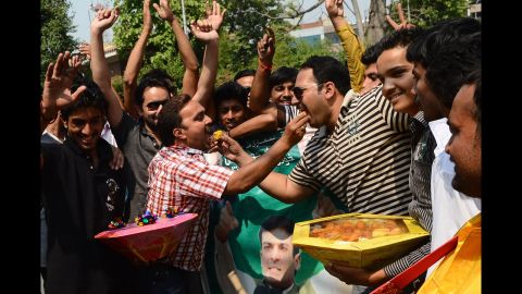 Supporters of Nawaz Sharif dance and eat sweets as they celebrate the party's win in Lahore on Wednesday, May 15.