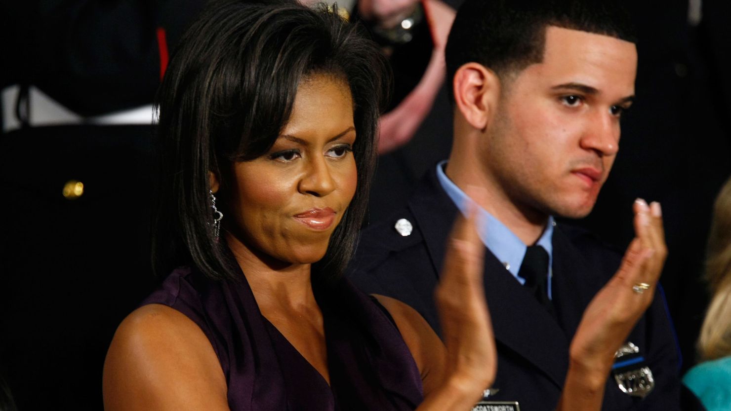 Officer Richard DeCoatsworth stands beside Michelle Obama during a presidential speech in 2009.