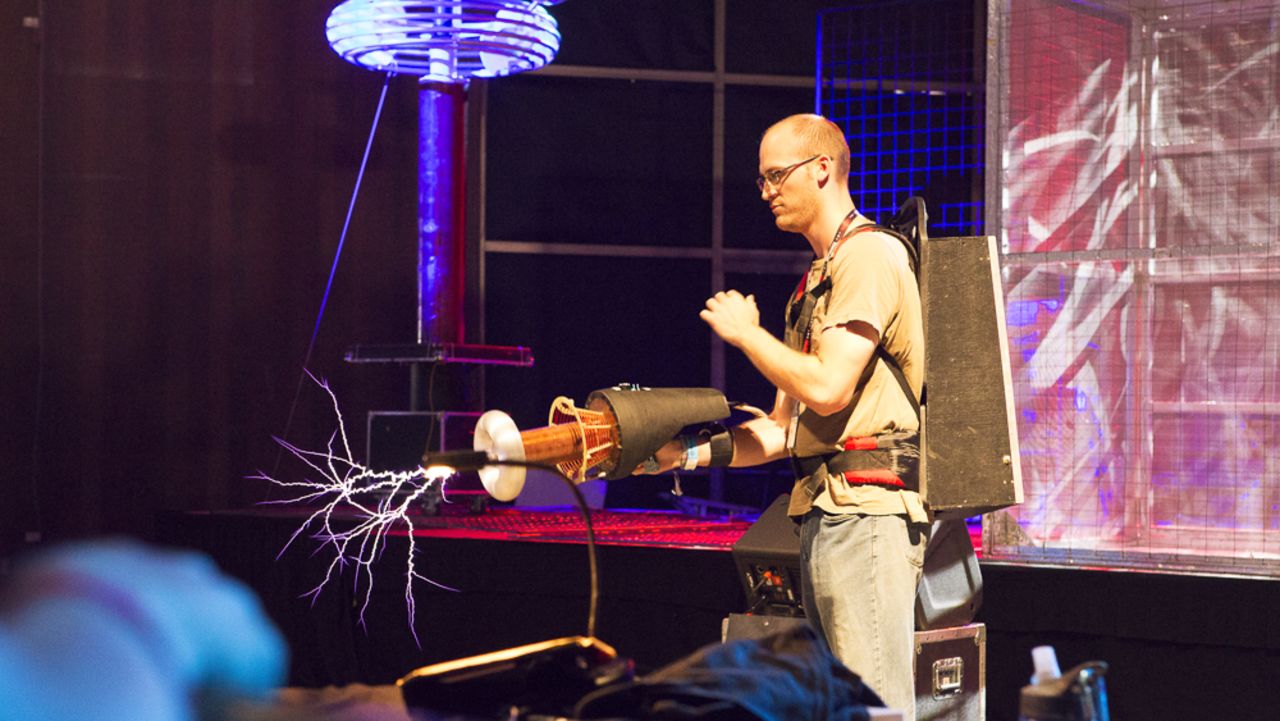 A man demonstrates the <a href="http://www.arcattack.com/" target="_blank" target="_blank">ArcAttack</a>'s portable Tesla coil in front of Tesla coils in the Maker Faire Fiesta Hall. 