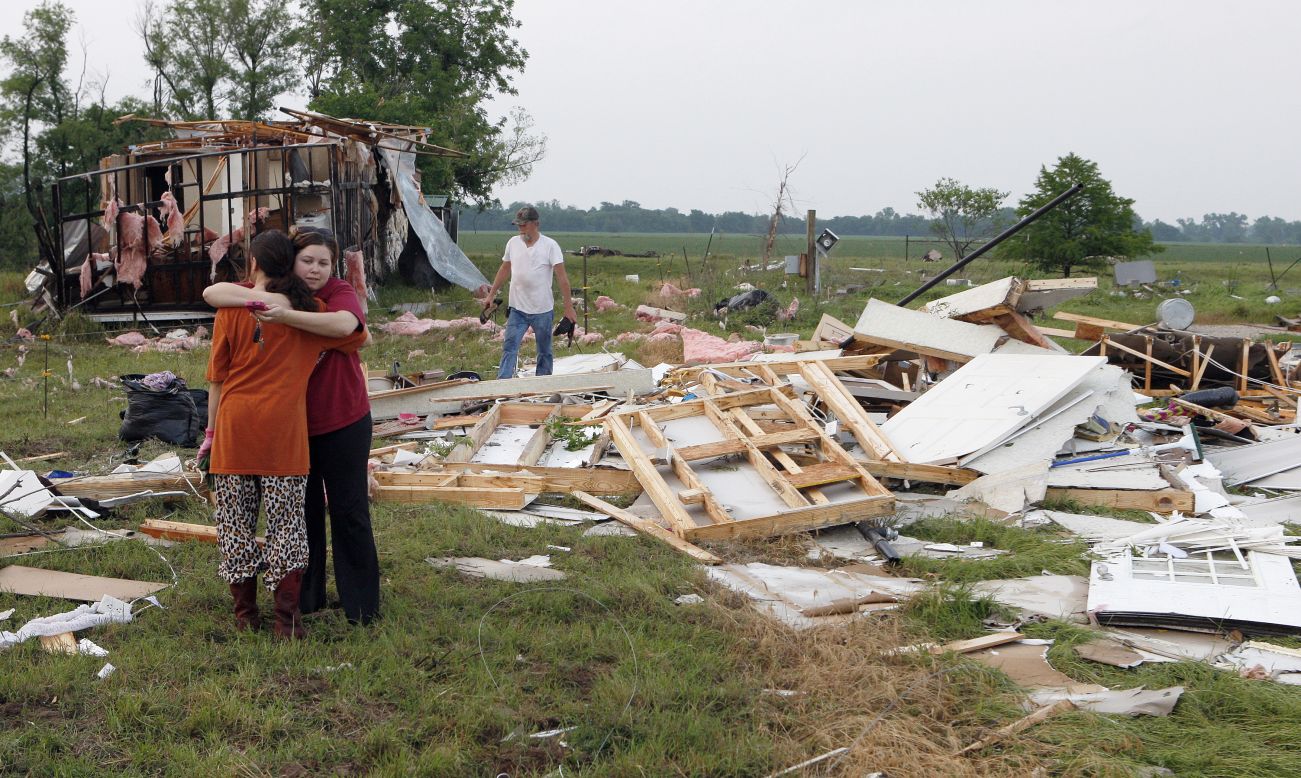 Shawnee residents embrace on May 20 as they search through the remains of their home.