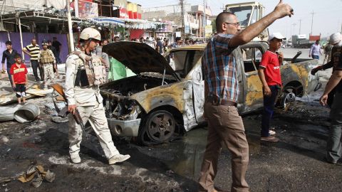 Iraqi citizens and soldiers inspect the scene of one of two car bombings in Basra on Monday.