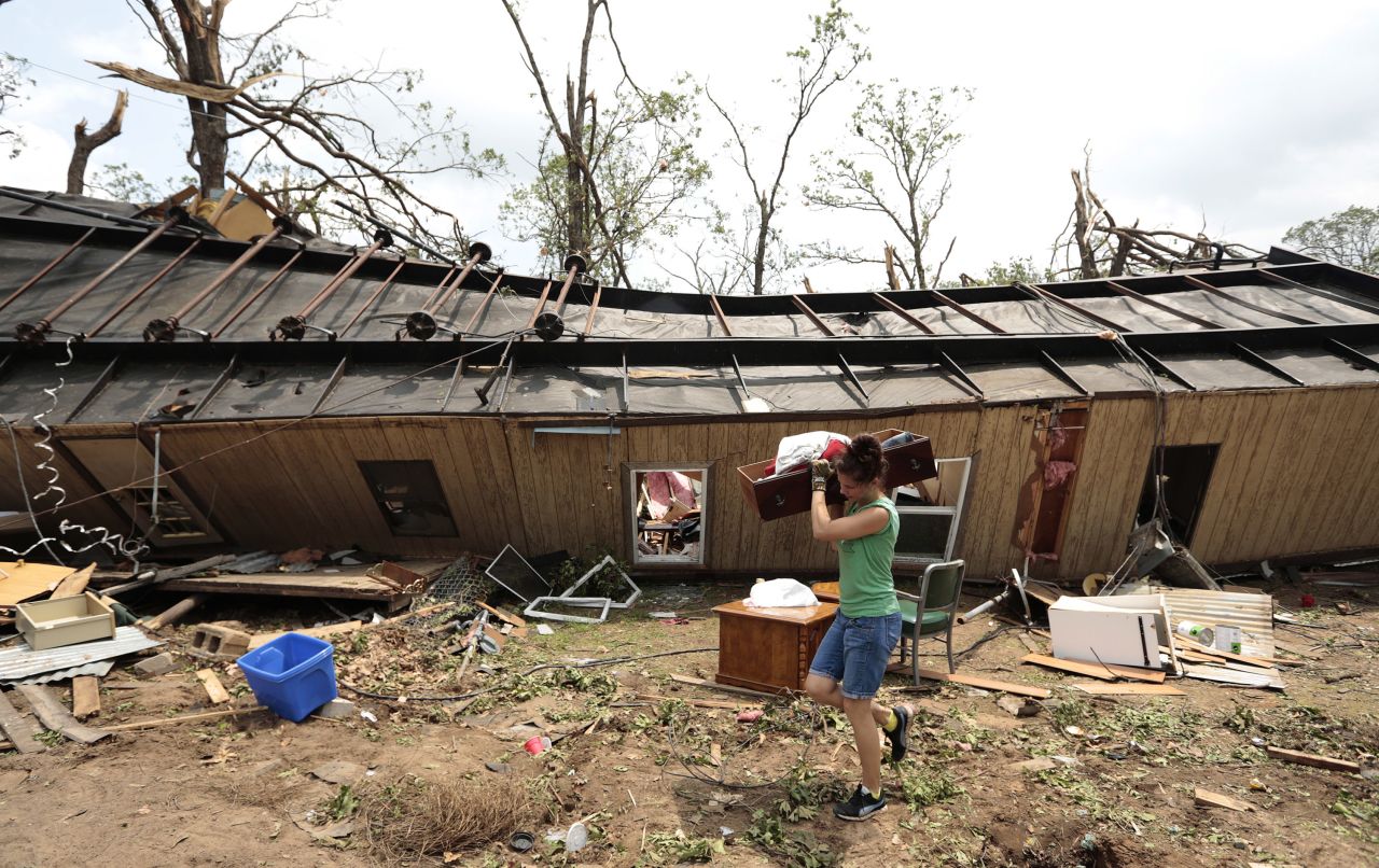 A volunteer helps clean up a mobile home on May 20 after it was overturned on a day earlier near Shawnee, Oklahoma.