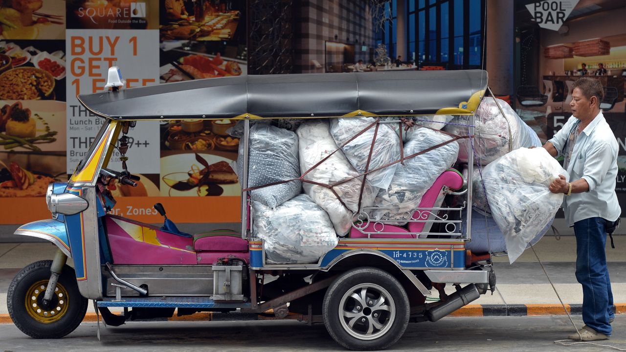 A Thai worker loads packs of clothes on a Thai tuk-tuk at shopping mall in Bangkok on May 20.