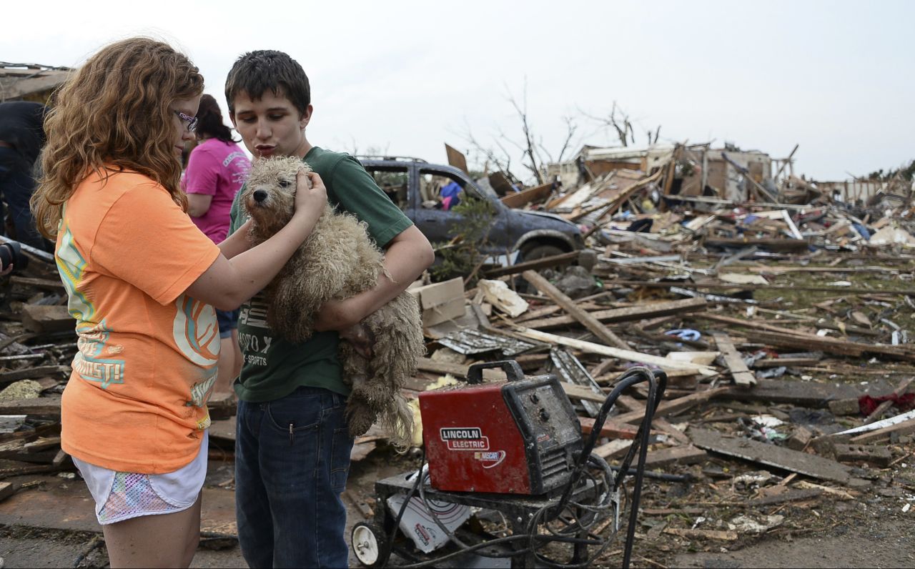 Abby Madi, left, and Peterson Zatterlee comfort Zatterlee's dog, Rippy, on Monday, May 20, in Moore.