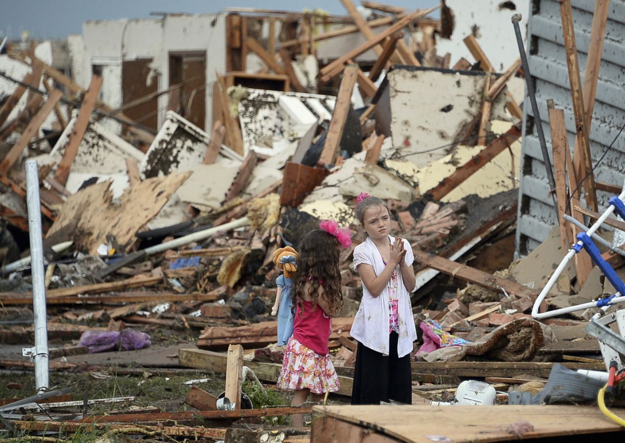 Two girls stand in rubble in Moore. 