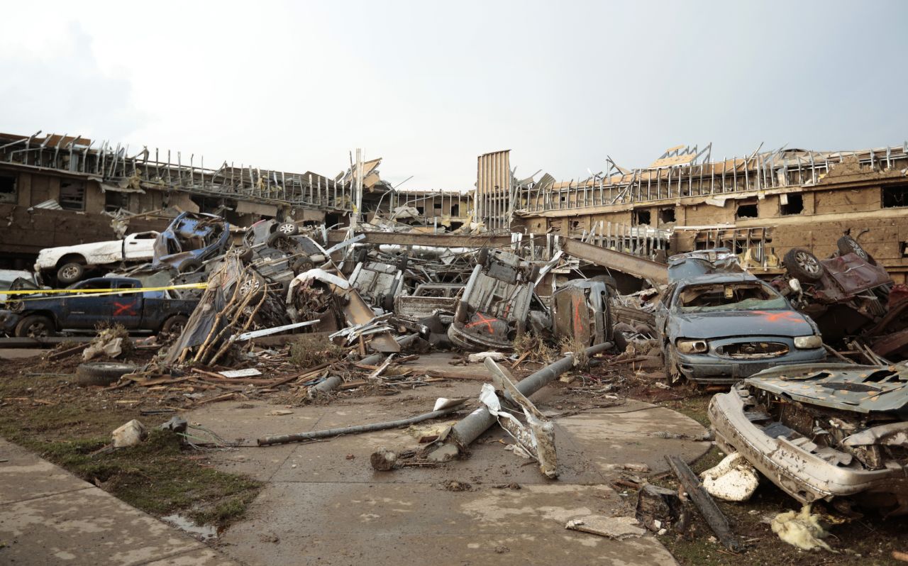 Cars marked with an orange X, meaning they have been checked for occupants, are piled up in front of the entrance to the damaged Moore Medical Center on May 20.
