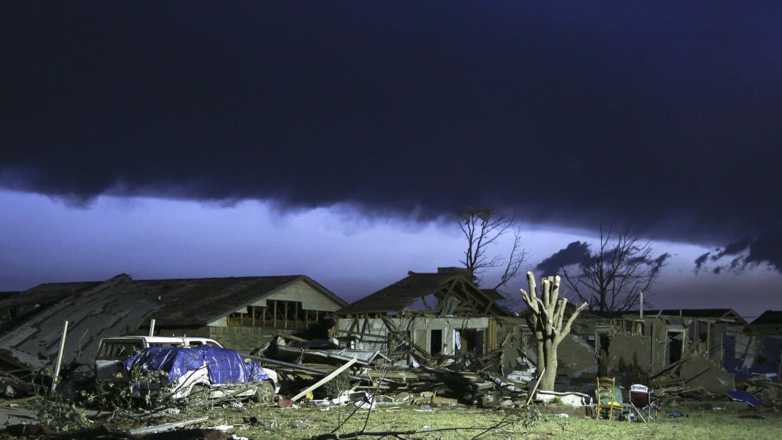 As dawn breaks, storm clouds roll in over a devastated neighborhood in Moore on May 21.
