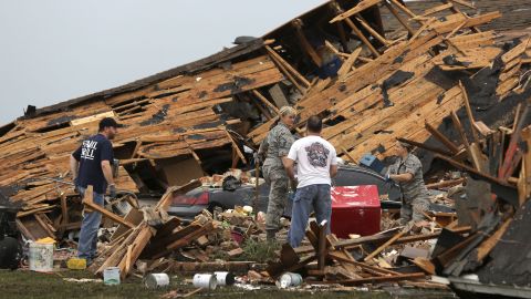People sort through a leveled home in Moore on May 21.