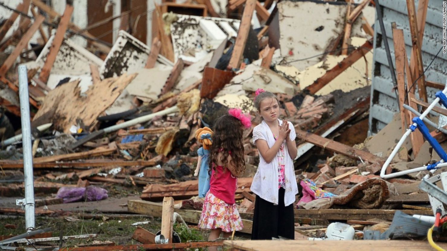 Two girls stand in rubble in Moore, Oklahoma. Melissa Brymer says parents can help kids by being honest and listening.