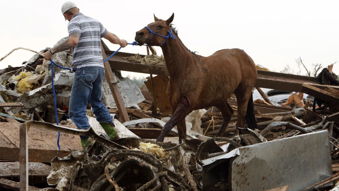 A rescue worker leads a horse from the wreckage of a day care center and barns on Monday, May 20, in Moore.