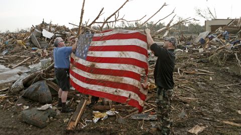 Men tie an American flag on debris in a neighborhood off Telephone Road in Moore on May 20.