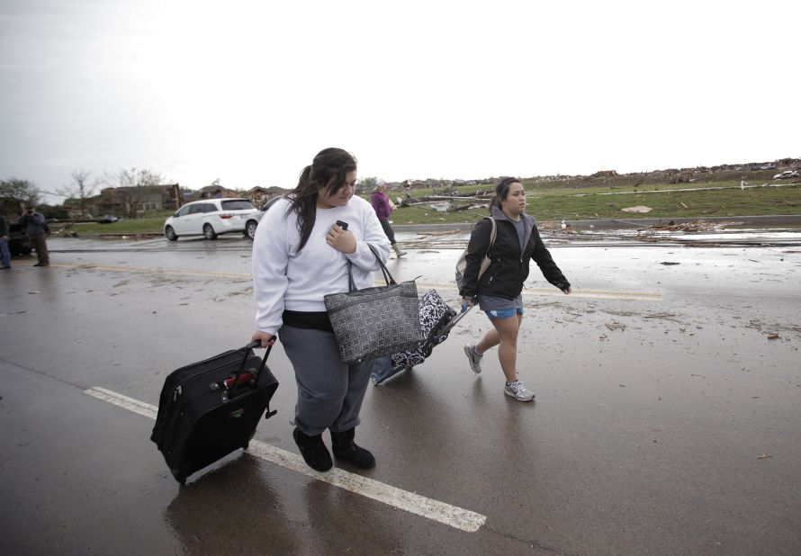 Bonnie Lolofie, left, and Ashley Do carry belongings from their apartment, which has no power, on May 21.