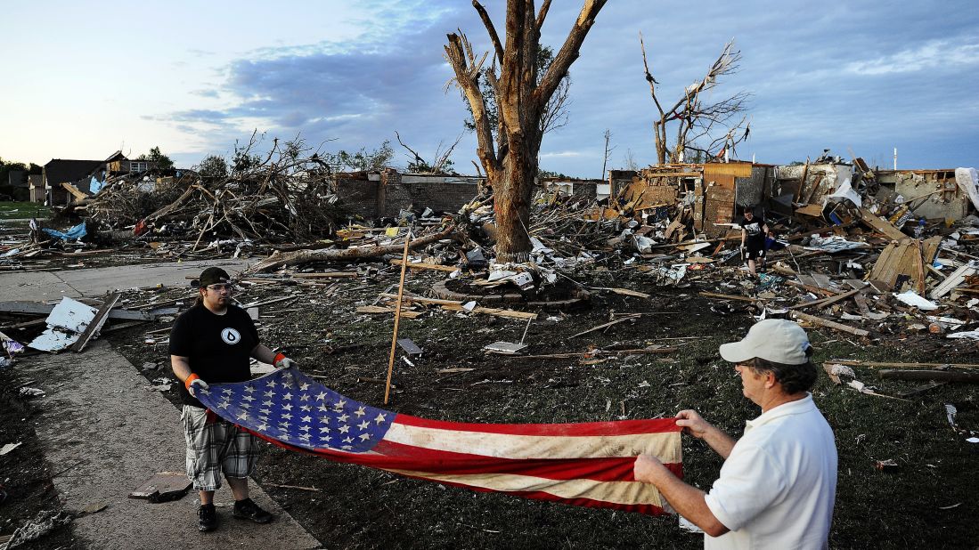 Two men fold an American flag found in the debris of a house on May 21 in Moore.