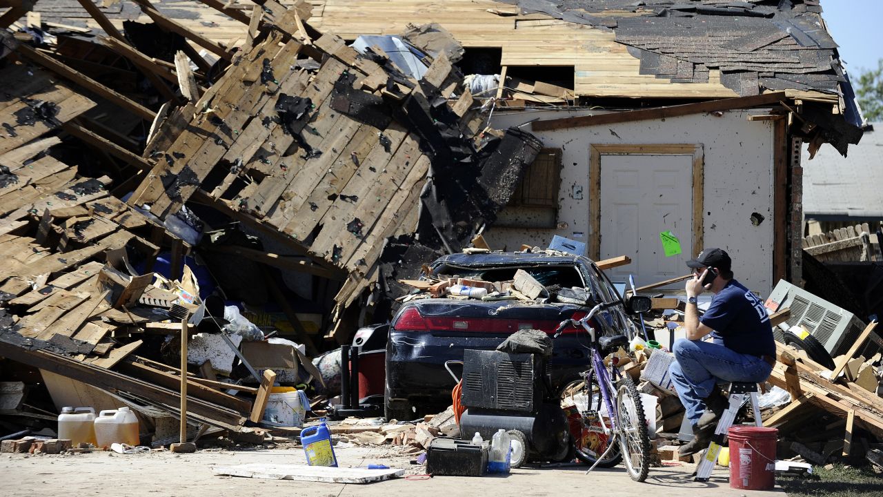 A man talks on his cell phone in front of a destroyed house on May 22.
