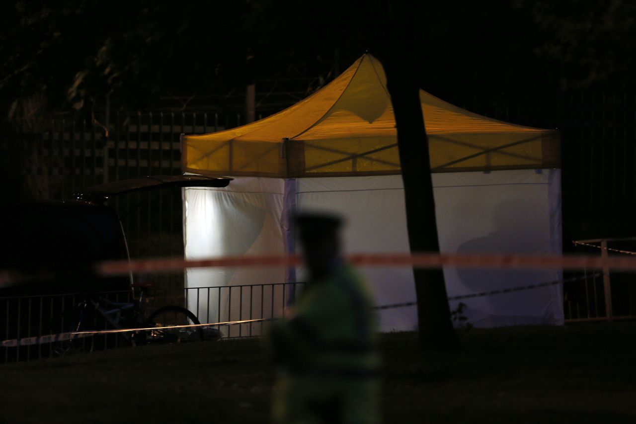 A police officer guards a tent that's been set up at the crime scene as investigations continue late May 22.