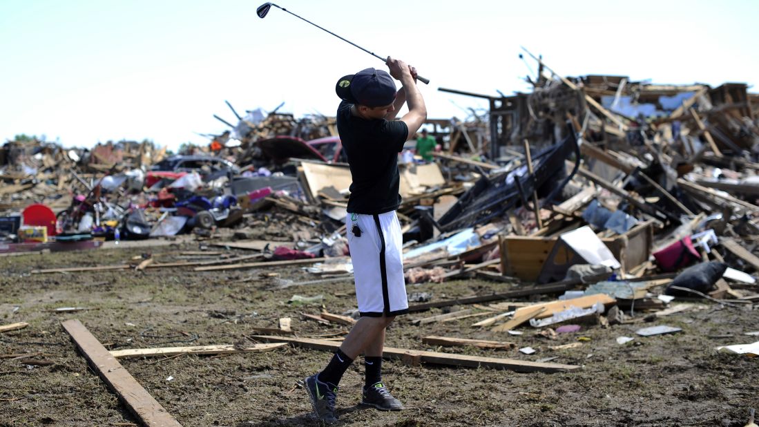 Michael Pritz swings a golf club while taking a break from helping his friend to salvage belongings on May 22.