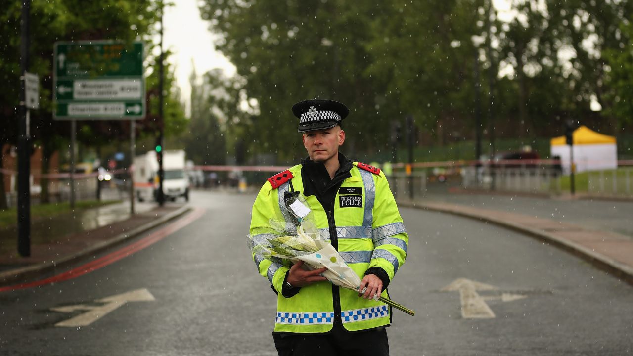 A police officer stands with flowers in a storm on Thursday, May 23, close to the crime scene in front of Woolwich Barracks in southeast London.