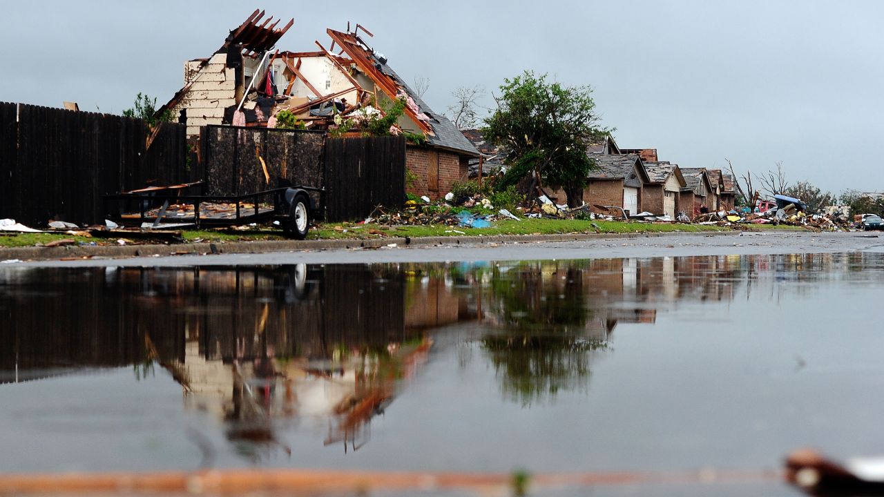 Rubble lines a wet street in a tornado-devastated neighborhood in Moore, Oklahoma, on Thursday, May 23. Severe thunderstorms barreled through this Oklahoma City suburb at dawn Thursday, complicating cleanup efforts three days after a powerful tornado ripped through the area. 