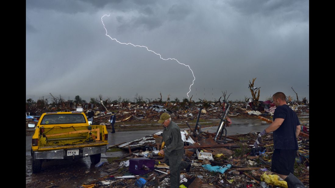 Lightning strikes during a thunderstorm as people search for items that can be saved from their devastated home on May 23.