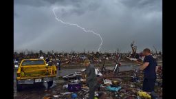 Lightning strikes during a thunder storm as people search for salvagable items at their devastated home on May 23, in Moore, Oklahoma.