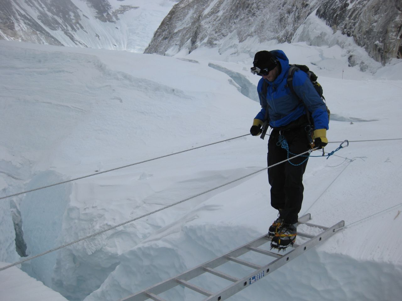 Kedrowski crosses a crevasse in the Khumbu Icefall on a ladder. Teaching clients how to walk in crampons and using other equipment in icy conditions is key to helping them acclimate.