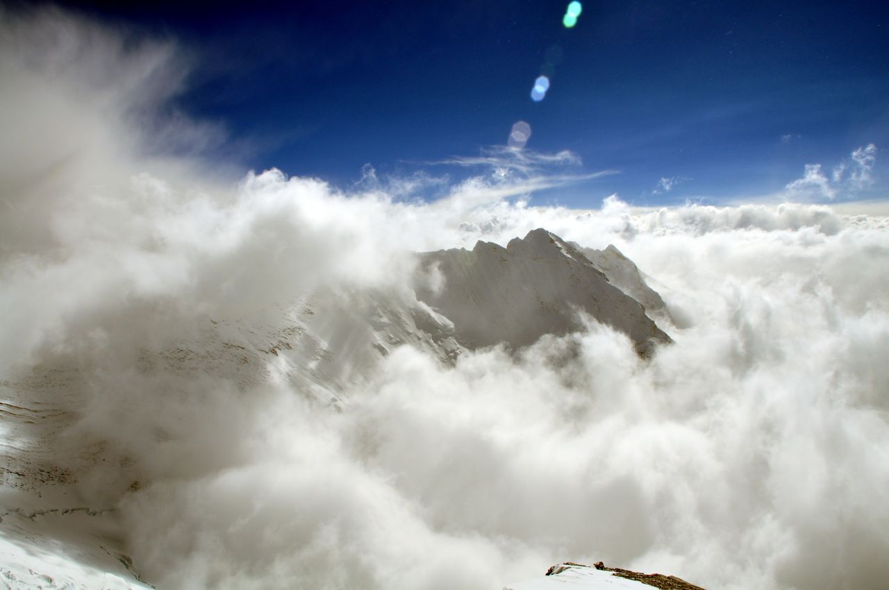 The peak of Nuptse, just over a mile southwest of Everest, is visible amongst the clouds in the Nepalese Himalayas.