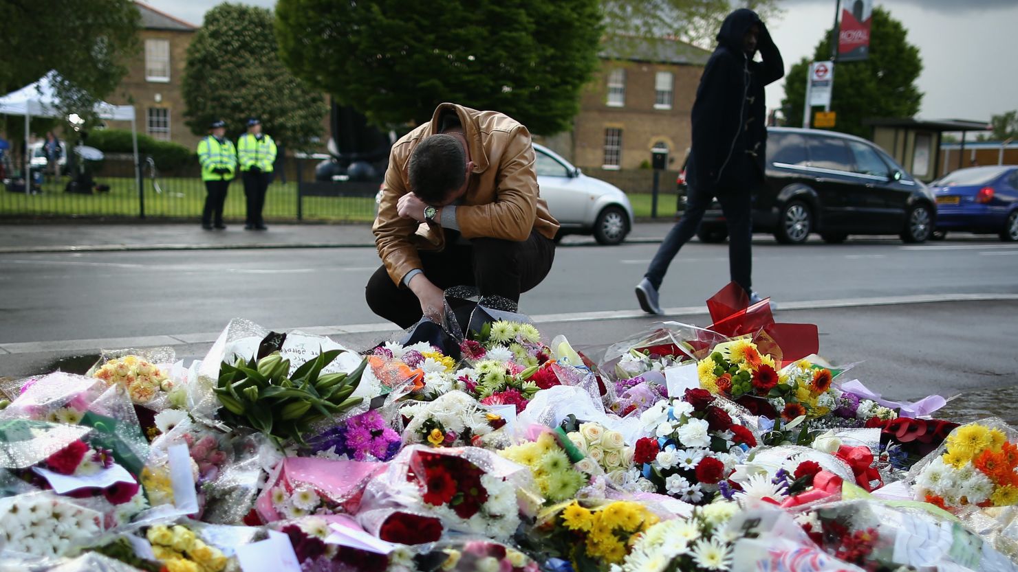 A man contemplates the scene where a British soldier was murdered in Woolwich, London; flowers have been laid in the street.