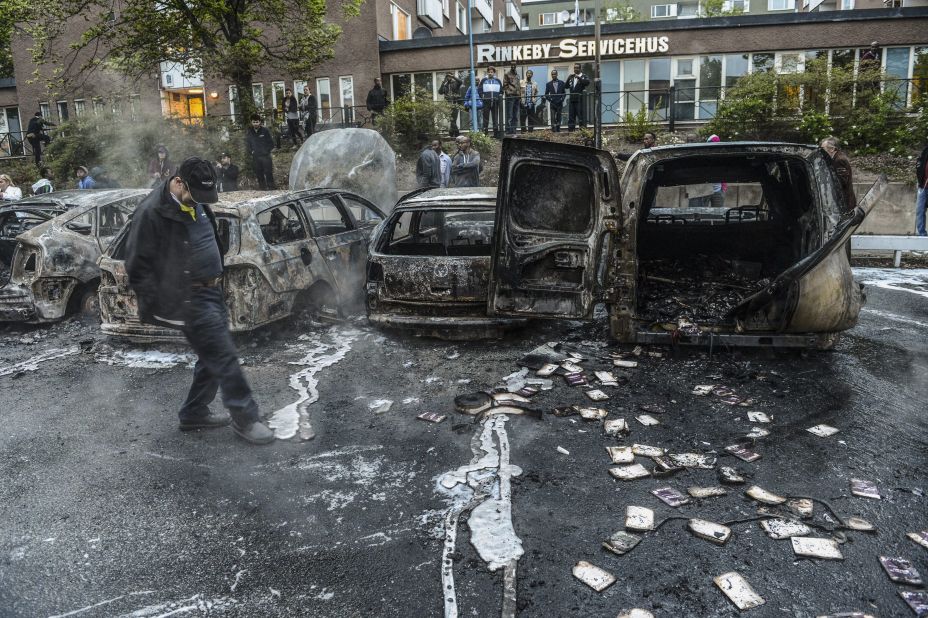 A man examines the debris around a row of burnt cars in the Stockholm suburb of Rinkeby on Thursday, May 23.