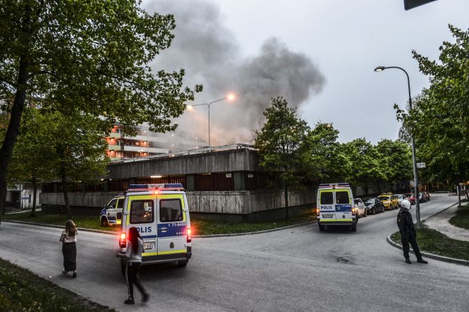 Police officers secure an apartment building after overnight riots in Husby on Monday, May 20. The building had to be evacuated after a fire spread inside the parking garage.
