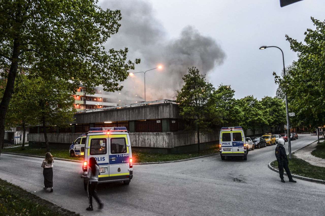 Police officers secure an apartment building after overnight riots in Husby on Monday, May 20. The building had to be evacuated after a fire spread inside the parking garage.