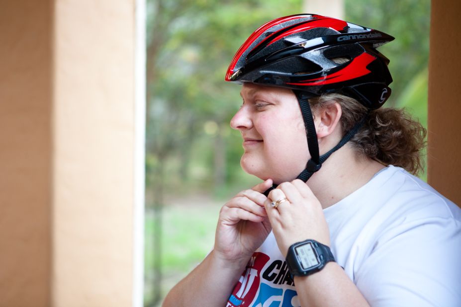 Tabitha McMahon straps on her helmet as she prepares for one of the group's training rides. 
