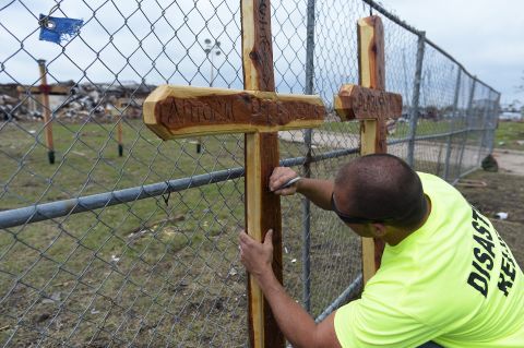 A volunteer signs a cross on May 25 at a makeshift memorial outside of the destroyed Plaza Towers Elementary School where seven children were killed in Monday's tornado in Moore.