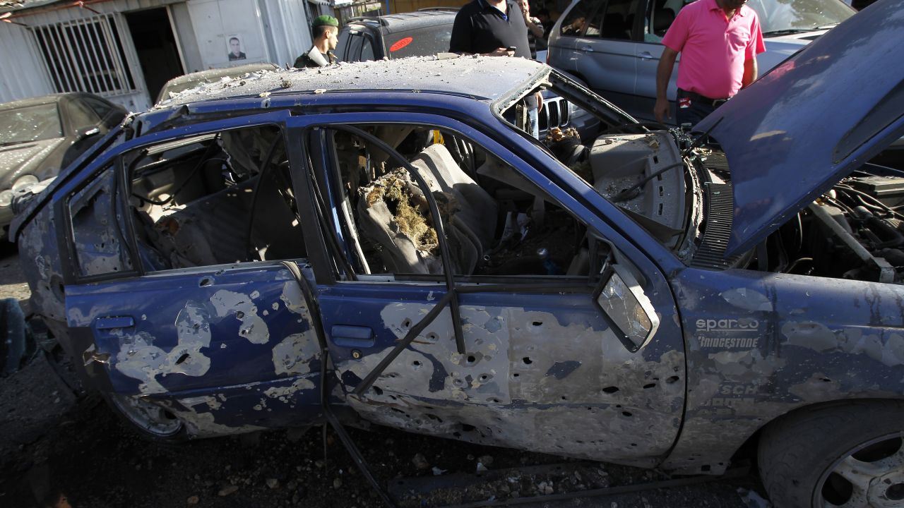 Lebanese men inspect destroyed cars after two rockets exploded in Shiah, a southern suburb of Beirut, on Sunday.
