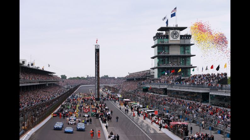 Balloons are released as cars, drivers and crews wait to start the race.